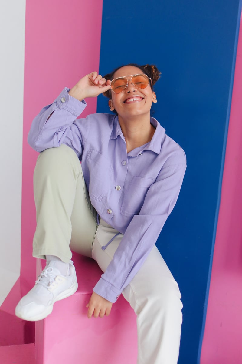 Jolly Young Girl in Sunglasses Sitting on Pink Stool